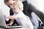 Father and toddler playing with laptop