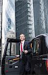 Businessman climbing out of taxi cab