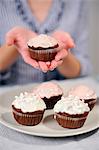 Woman holding plate with five muffins