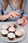 Woman putting garnish on muffins on plate