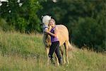 Smiling girl with horse on meadow