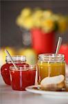 Various jars of jam, chutney and marmalade (strawberry, pepper, orange) and white bread