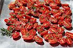 Tomatoes with rosemary on a baking tray to dry