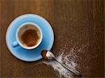 Une tasse à espresso presque vide et sucre saupoudré à côté d'elle