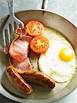 English breakfast with fried egg, sausages, bacon and tomatoes