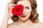 Woman covering eye with red rose