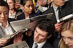 Businesspeople reading newspapers on crowded train