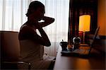 Young woman sitting at laptop in hotel room