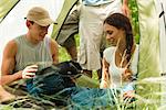 Young couple unrolling sleeping bag in tent