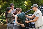 Young campers unloading backpacks from back of pick-up trucks