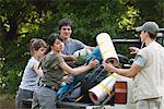 Young campers loading camping gear onto back of pick-up truck