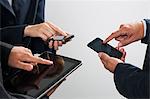 Colleagues exchanging information with smartphones and digital tablet, cropped