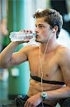 Barechested young man drinking bottled water