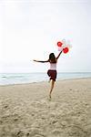 Frau am Strand mit Haufen Luftballons, Rückansicht