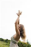 Young woman dancing with arms raised above head