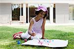 Girl sitting on grass drawing on paper