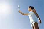 Female athlete holding up torch, low angle view