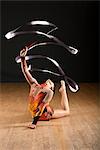 Gymnast bending backwards on floor, twirling ribbon