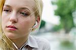 Young woman listening to earphones, looking away, portrait