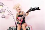Portrait d'une femme tatouée portant corset tout en maintenant la guitare contre le mur