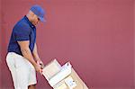 Side view of muscular African American delivery man with handtruck