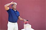 Glückliche junge Afroamerikaner Lieferung Mann mit Handtruck über farbigen Hintergrund