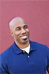 Happy bald African American man looking away over colored background