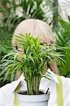 Close-up of a pot plant in front of senior woman's face