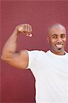 Portrait of an African American male flexing muscles over colored background