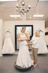 Schöne Frau, verkleidet als Braut mit leitenden Angestellten helfen im Hochzeits-Shop