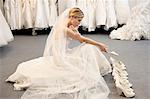 Seitenansicht einer jungen Frau im Hochzeitskleid verwirrt während der Auswahl Schuhe