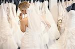 Vue arrière d'une jeune femme en robe de mariée robes de mariée en regardant exposée dans la boutique