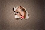 Young Middle eastern woman looking up from ripped paper hole