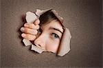 Portrait of a young Middle eastern woman peeking from ripped white paper hole