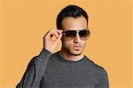 Stylish young man wearing sunglasses over colored background