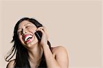 Cheerful young woman talking on mobile phone over colored background