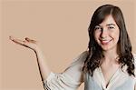 Portrait of a happy young woman with empty hand over colored background