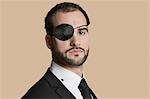 Portrait of a young businessman with eye patch over colored background