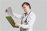 Männlichen Arzt in einem Laborkittel lesen medizinische Aufzeichnungen über grauen Hintergrund