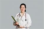 Portrait d'un femme asiatique médecin tenant un presse-papiers sur fond gris