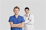 Porträt des männlichen Krankenschwester und Arzt stehend mit Arme verschränkt auf grauem Hintergrund