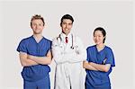 Portrait of multi ethnic healthcare professionals standing with arms crossed over gray background