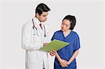 Doctor discussing medical report with female nurse over gray background