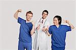 Portrait of a cheerful medical team gesturing over gray background