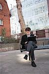 Young businessman working on laptop while sitting on bench