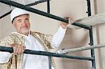 Portrait of mature man climbing scaffold