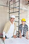 Team of architects looking away with blueprints at table