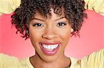 Close-up portrait of an African American woman smiling over colored background