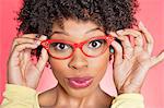 Portrait of an African American woman wearing retro style glasses over colored background