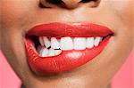 Close-up view of an female biting her red lip over colored background